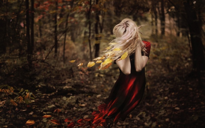 Woman with blonde hair in a red dress in a forest