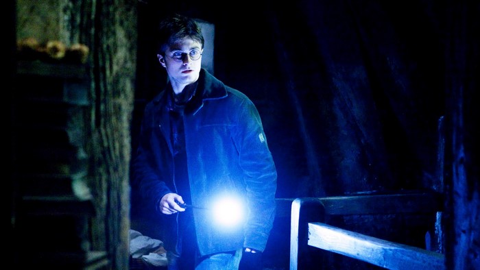 Daniel Radcliffe as Harry Potter holding a wand