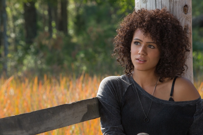 Nathalie Emmanuel leaning on a wooden post