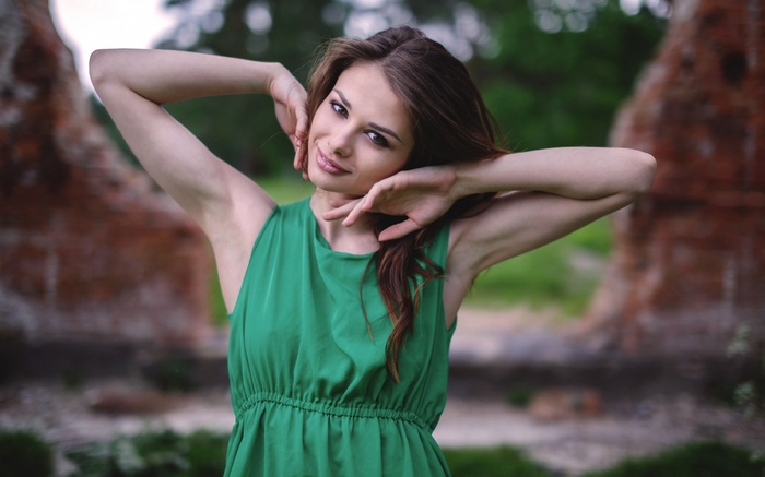 Woman in green dress with arms raised