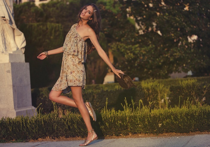 Clara Alonso in a floral dress holding a bag