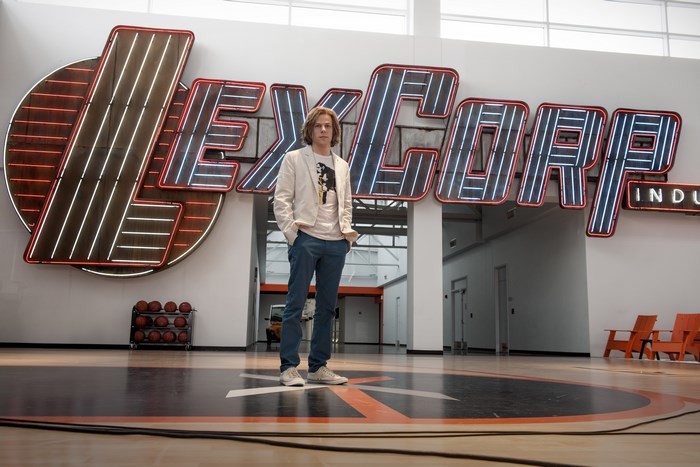 Jesse Eisenberg in front of LexCorp sign