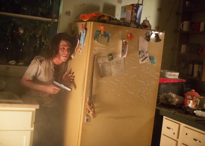 Jesse Eisenberg with a gun in a kitchen