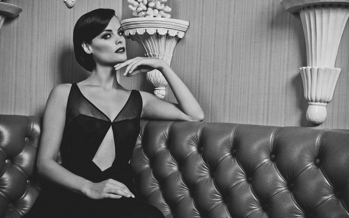 Jaimie Alexander in a black dress on a couch