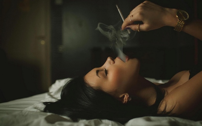 Woman smoking a cigarette in bed