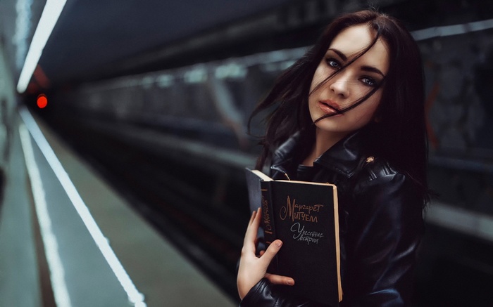 Woman holding a book on a subway platform