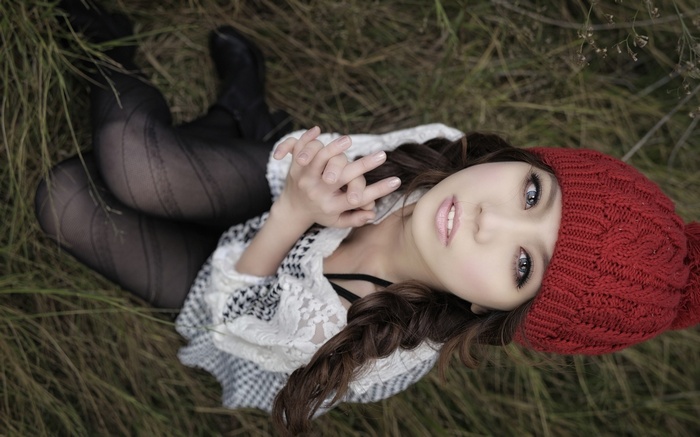 Woman in red hat lying in grass