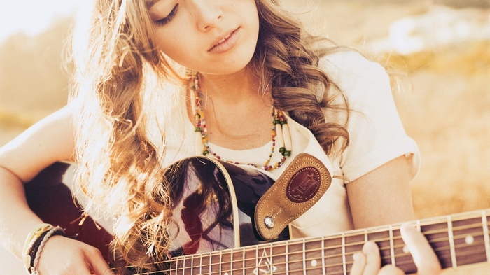 Young woman playing acoustic guitar outdoors