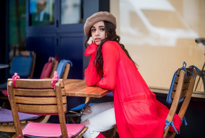 Camila Cabello sitting at a cafe table
