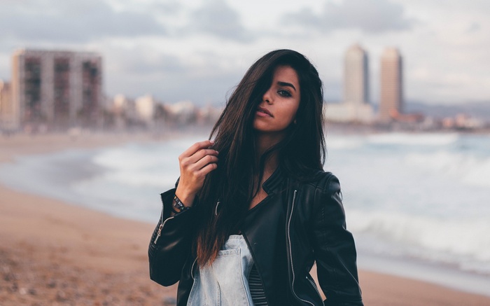 Woman on a beach with city in background