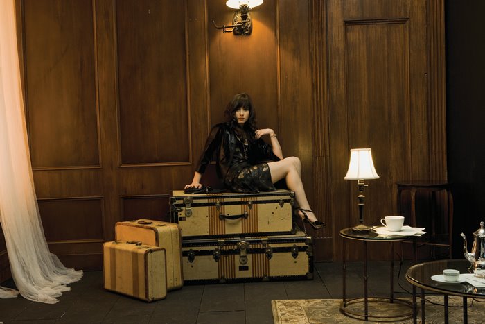 Demi Lovato sitting on vintage luggage