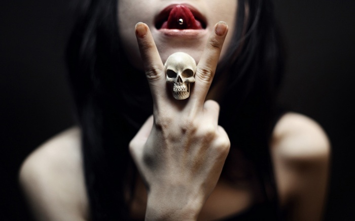 Woman with tongue piercing and skull ring