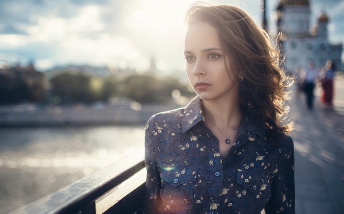 Woman on a bridge with city in background