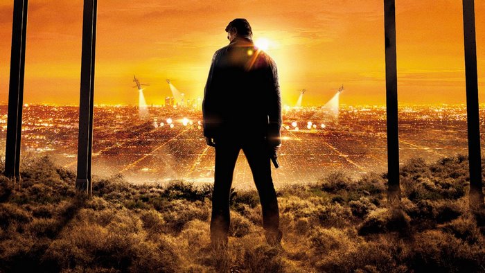 Liam Neeson in a city at sunset