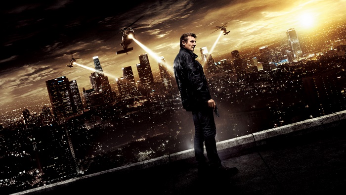 Liam Neeson on a rooftop with helicopters over city