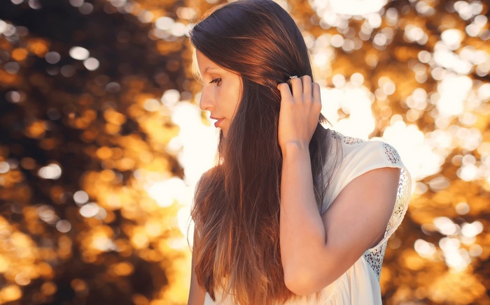 Woman with long brown hair touching her hair