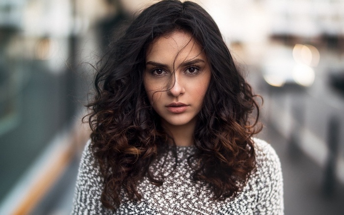 Woman with curly dark hair wearing a sweater