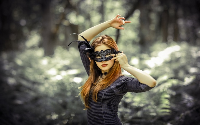 Woman in a masquerade mask in a forest