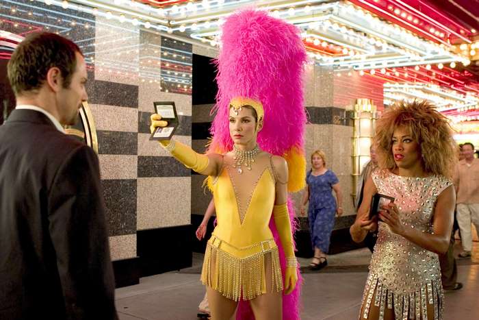 Sandra Bullock in a yellow costume with a pink feather boa