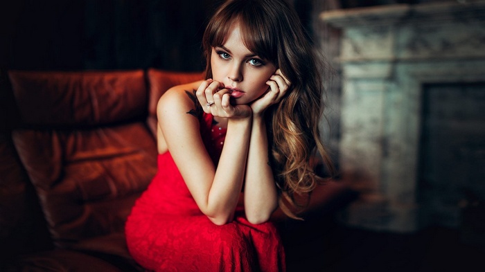 Woman in red dress sitting on a leather couch