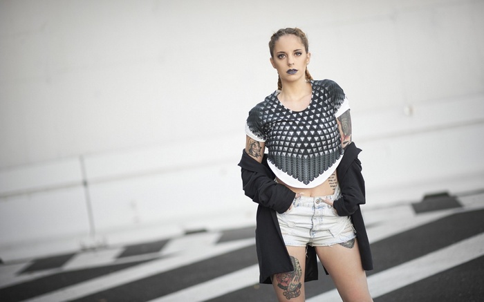 Woman with tattoos wearing crop top and shorts
