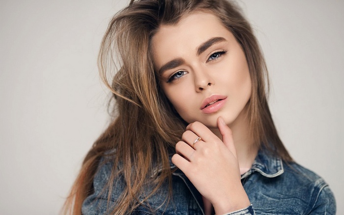 Woman with long brown hair wearing denim jacket