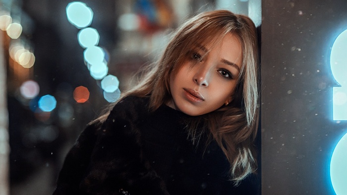 Woman leaning against a wall with bokeh lights