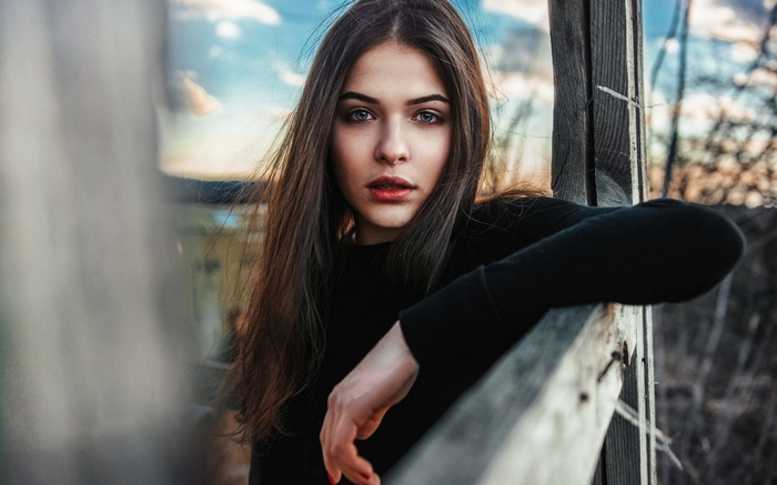 Woman leaning on a wooden fence