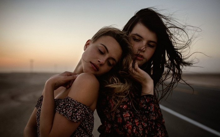 Two young women embracing at sunset