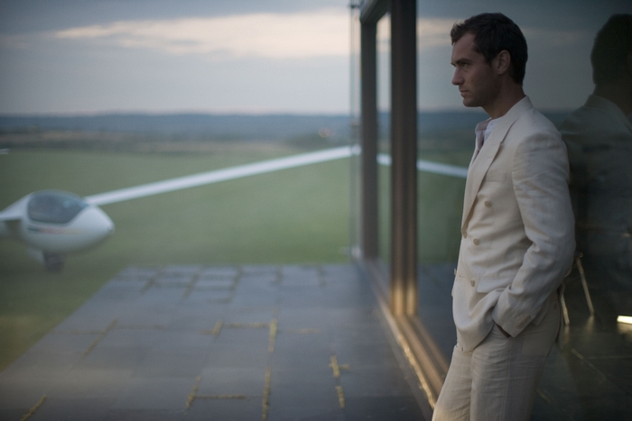 Jude Law in a suit by a window