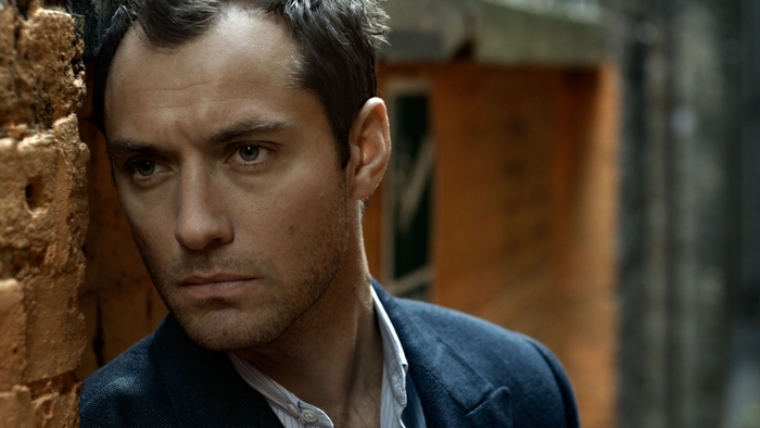 Jude Law leaning against a brick wall