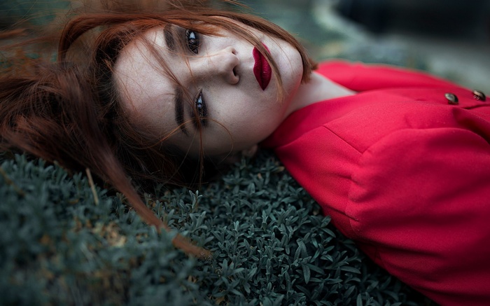 Woman in red jacket lying on grass
