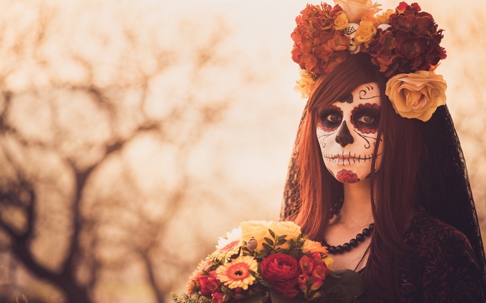 Woman in Day of the Dead makeup holding flowers