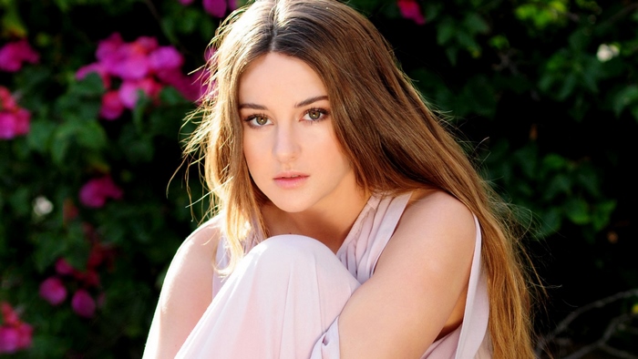 Shailene Woodley posing outdoors with pink flowers