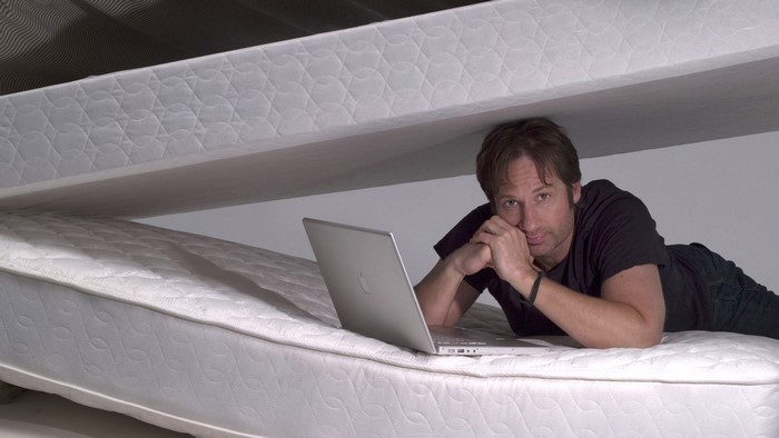 David Duchovny lying on mattresses with laptop
