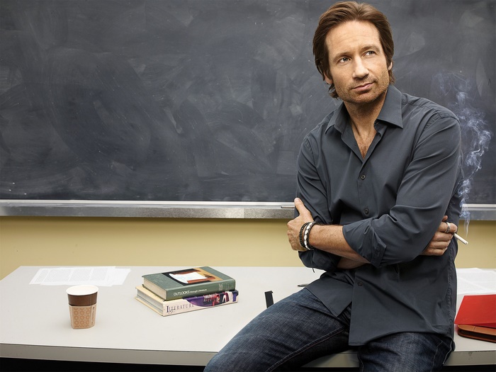 David Duchovny sitting in front of a blackboard