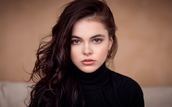 Woman with dark wavy hair wearing a black turtleneck