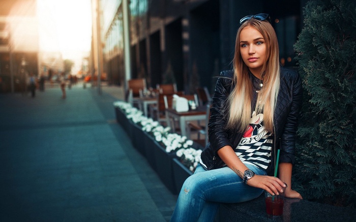 Woman in leather jacket and jeans holding a drink