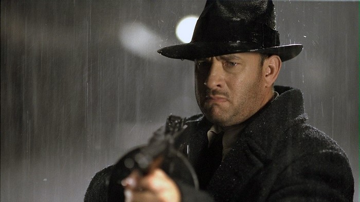 Tom Hanks in the rain holding a gun