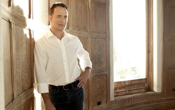 Tom Hanks leaning against a wooden wall