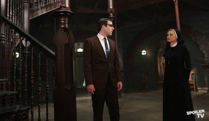 Zachary Quinto and nun in a dark hallway