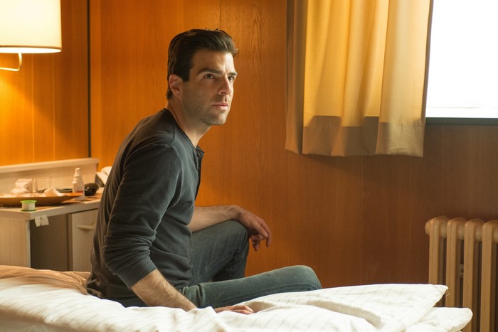 Zachary Quinto sitting on a bed