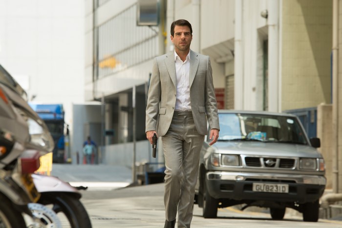 Zachary Quinto in a suit holding a gun