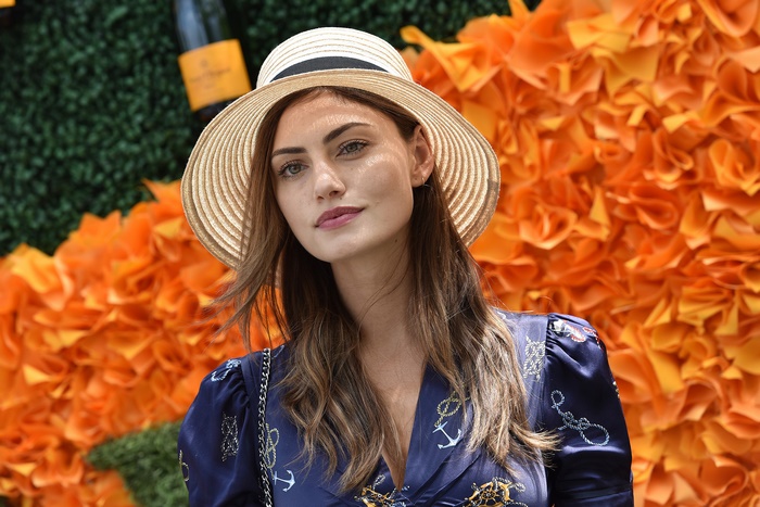 Phoebe Tonkin wearing a straw hat and navy dress