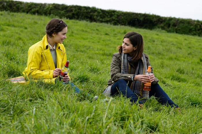 Jenna Coleman sitting in a field