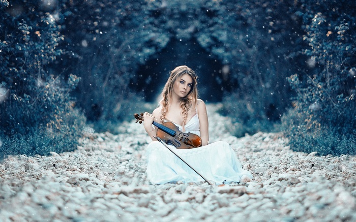 Woman with violin in a snowy forest