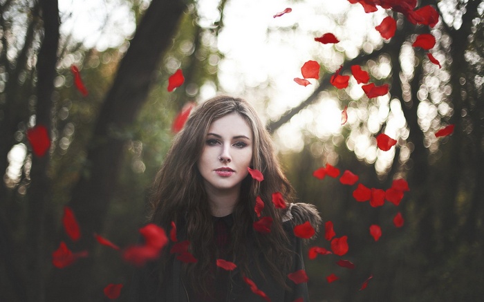 Woman with red petals falling around her