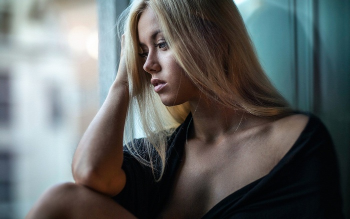 Woman with blonde hair looking out a window