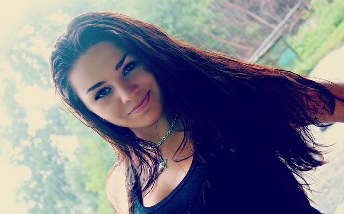 Woman with long dark hair wearing a black tank top