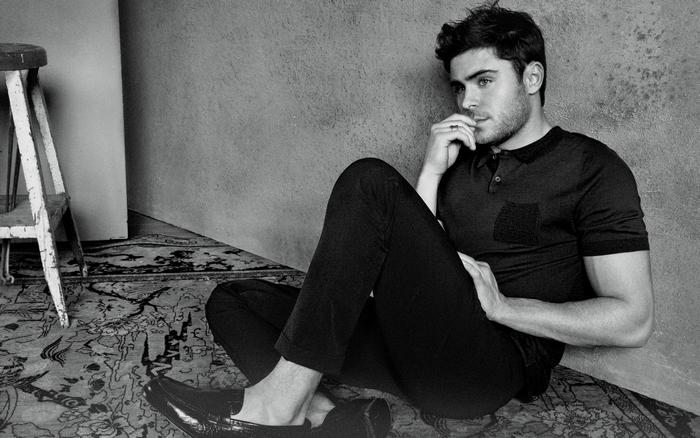 Zac Efron sitting on a rug